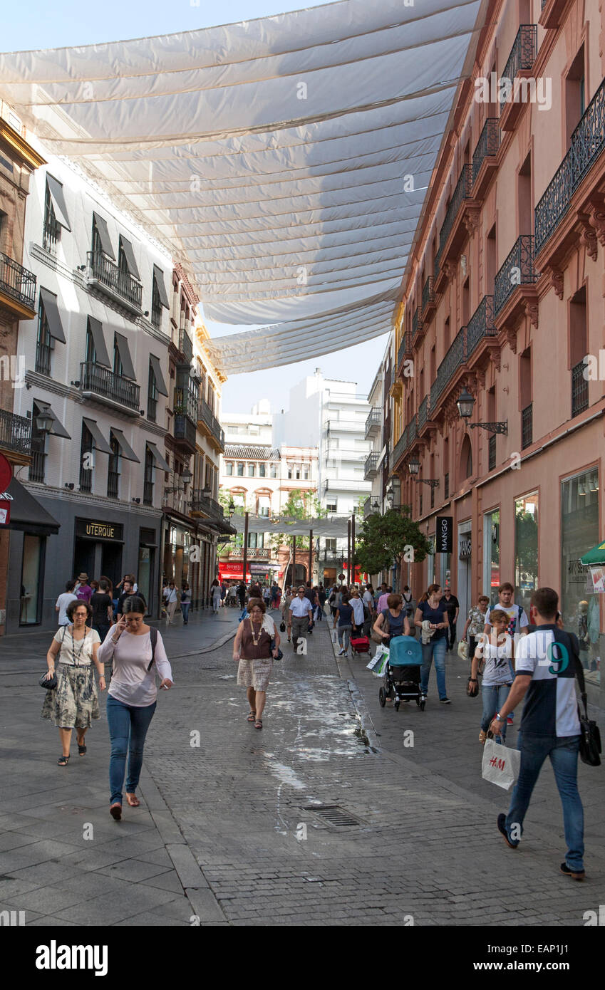 Fabric spread over buildings to provide shade in busy shopping street in  central Seville, Spain Stock Photo - Alamy