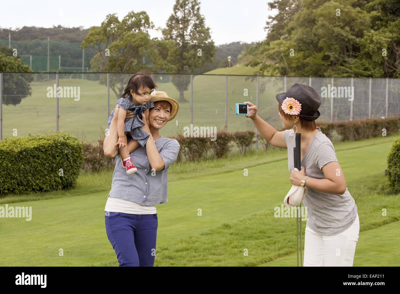 Family on a golf course. A woman using a camera. Stock Photo