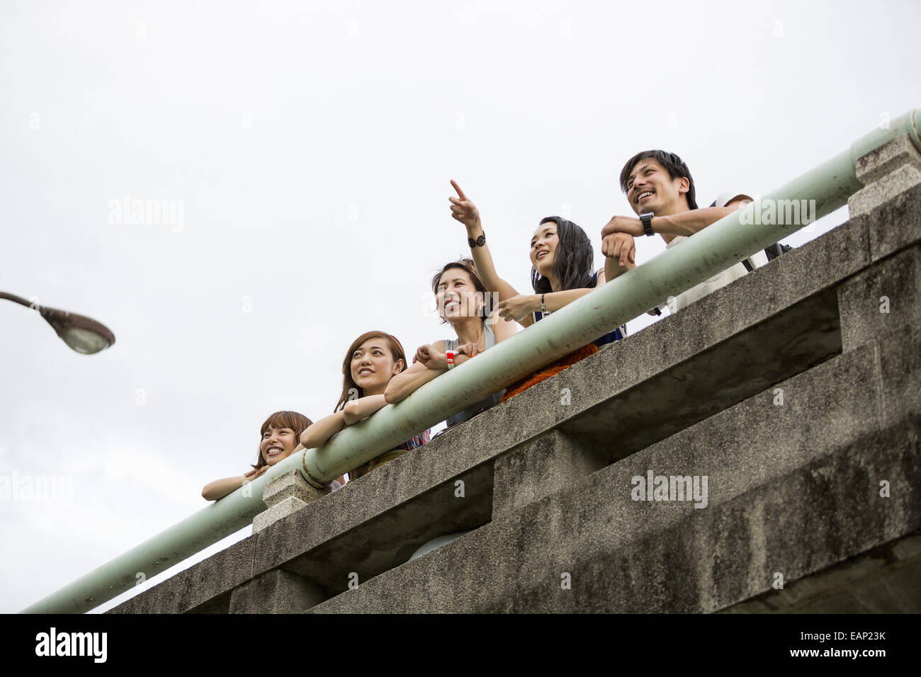 Friends in the park leaning on a parapet. View from below. Stock Photo