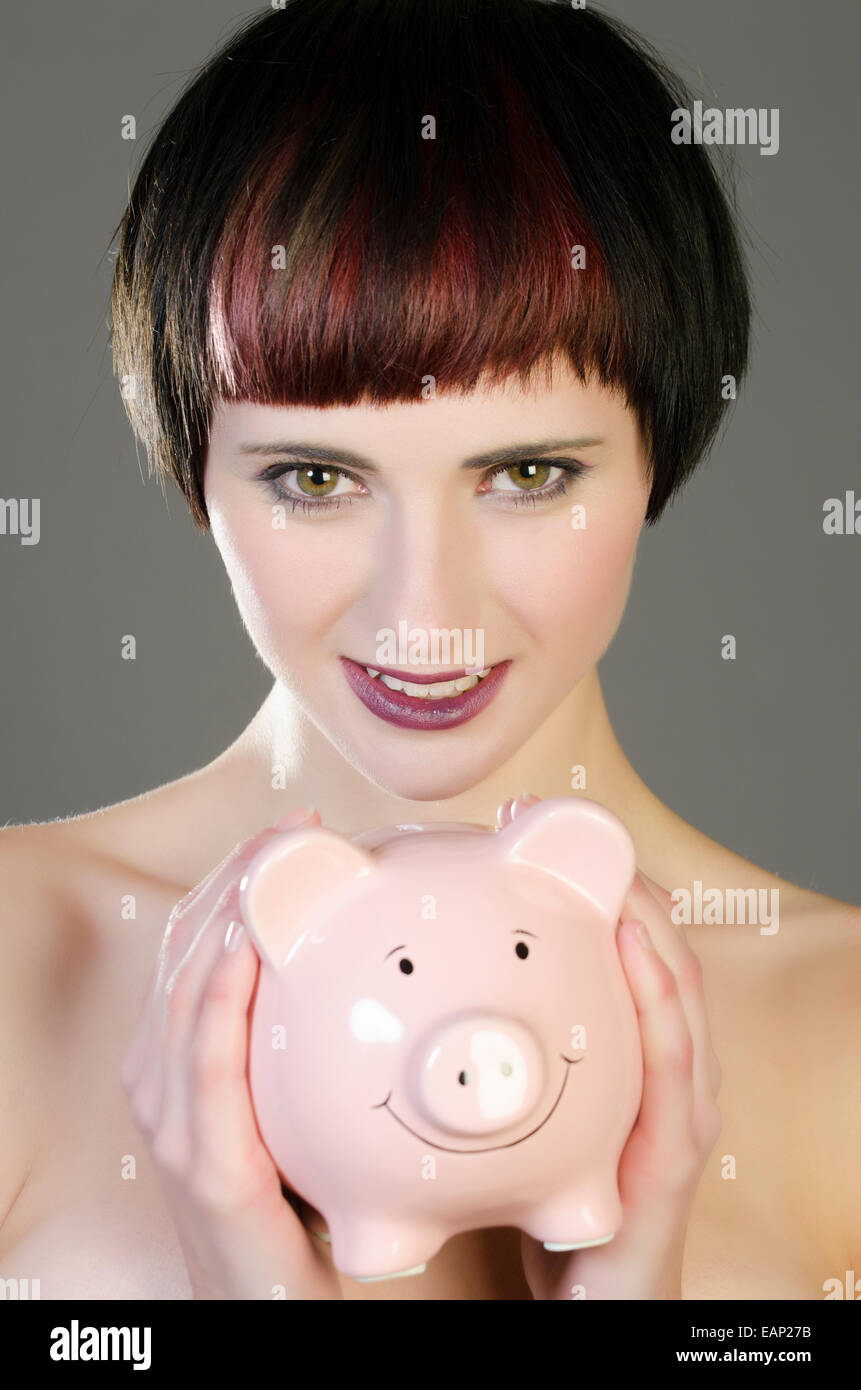 Beautiful young woman holding a piggy bank smiling Stock Photo - Alamy