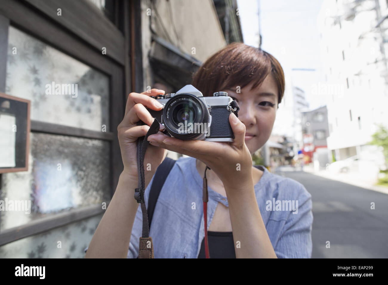 Woman standing outdoors, looking through a camera. Stock Photo