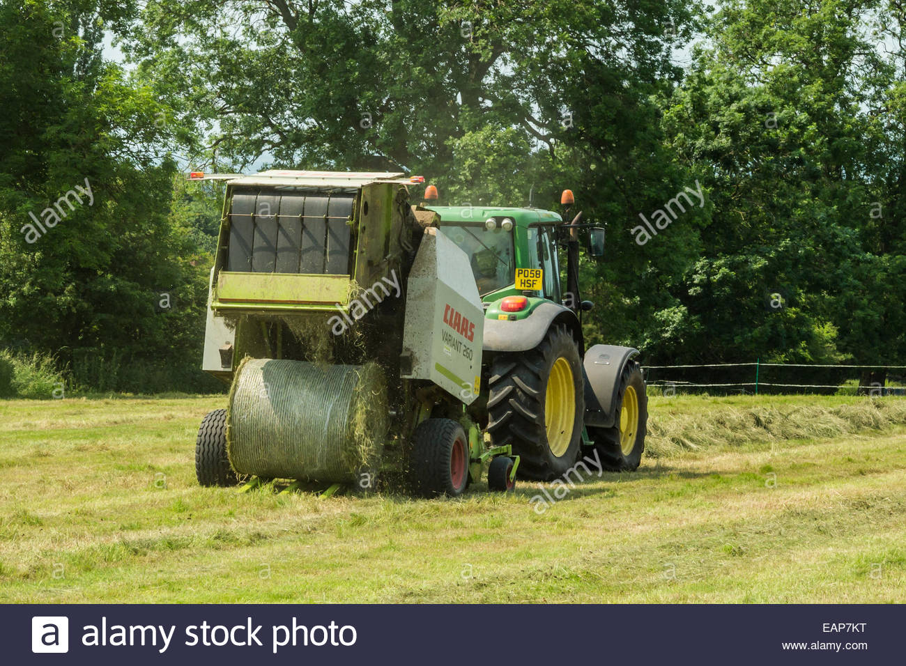 Tractor pulling baling machine in field making hay bales Stock Photo