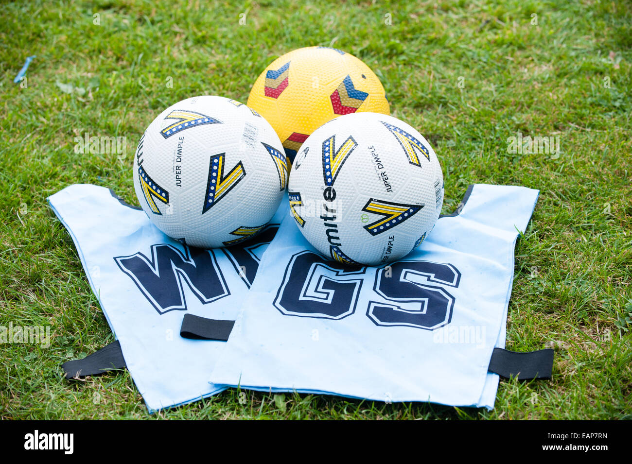 Clean white netball tabards and three netball balls on the grass at a school coaching course Stock Photo