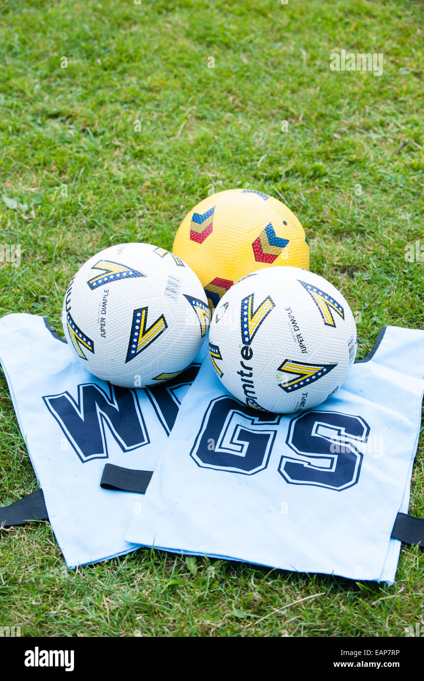 Clean white netball tabards and three netball balls on the grass at a school coaching course Stock Photo
