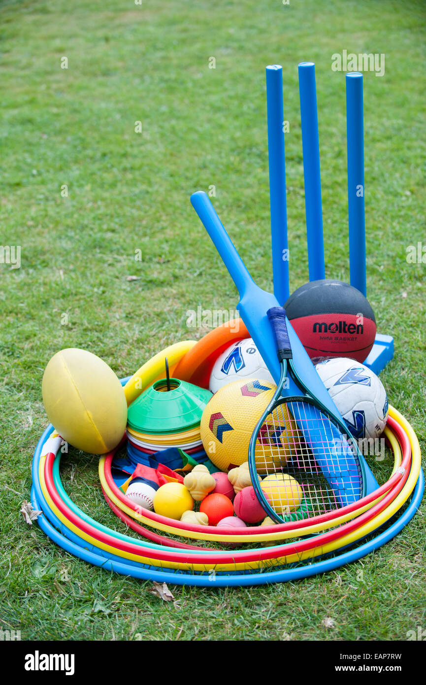Brightly coloured plastic children's sports equipment with cricket bats, balls, tennis raquet and hoops on a coaching course Stock Photo