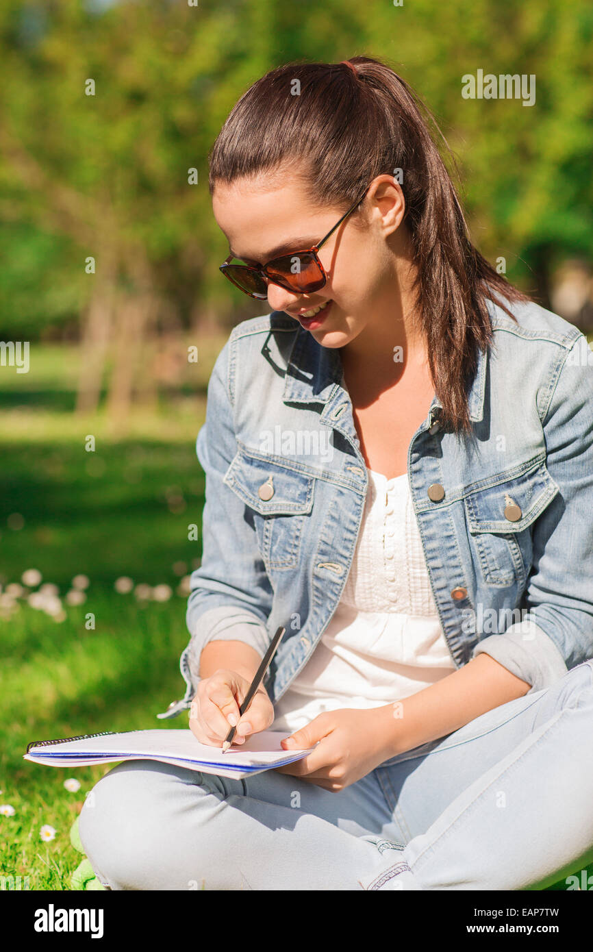 smiling young girl with notebook writing in park Stock Photo - Alamy