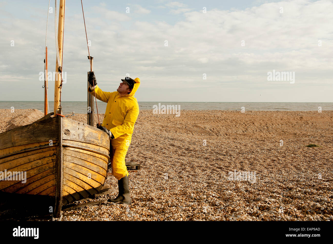 Sea fisherman wearing yellow waterproof overalls, preparing his fishing  boat Stock Photo - Alamy