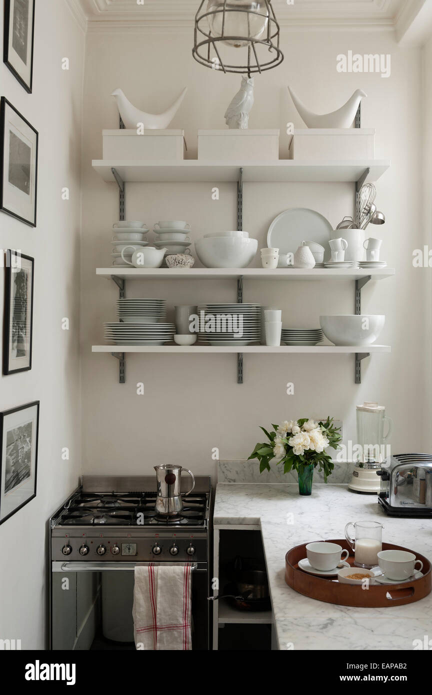 White crockery on open shelving in galley style kitchen with marble