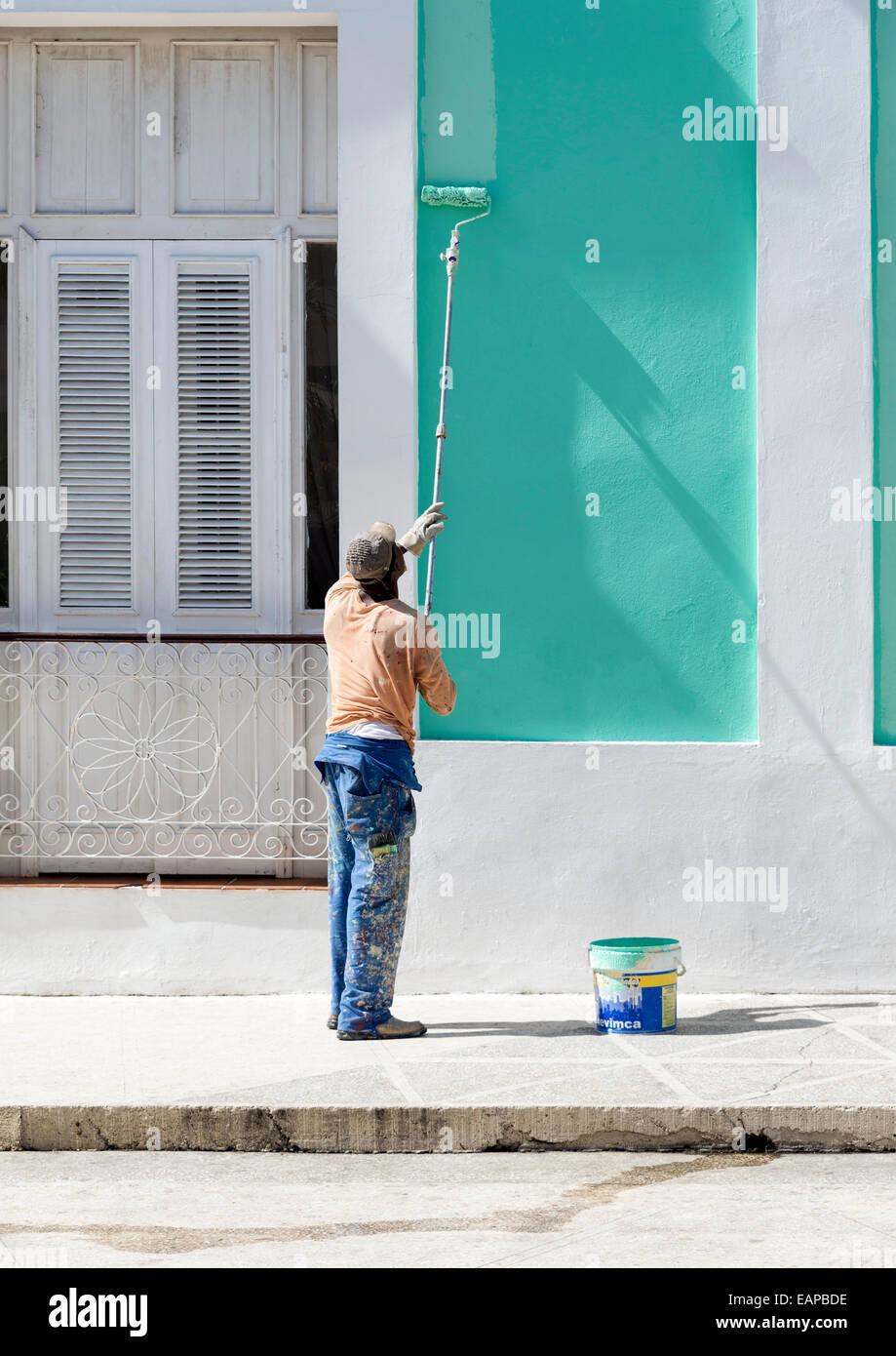 CIENFUEGOS, CUBA - MAY 7, 2014: A man paints the facade of a house in the city center Stock Photo