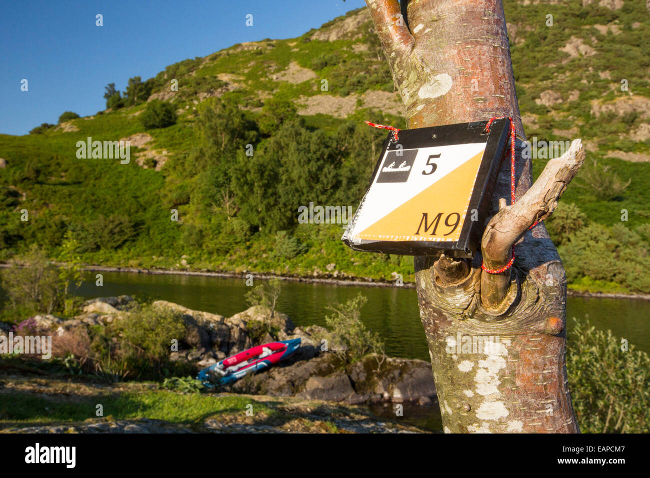 A kayak orienteering marker on an island with an inflateable kayak on Ullswater in the Lake District, UK. Stock Photo