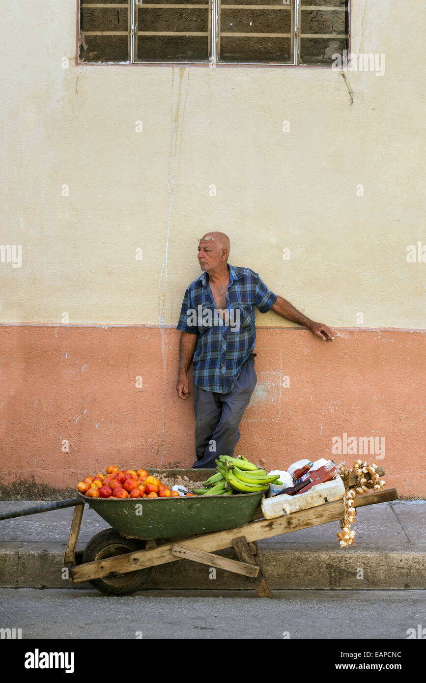 MATANZAS, CUBA - MAY 10, 2014: Fruit peddler waits for customers on the shady side of the street Stock Photo