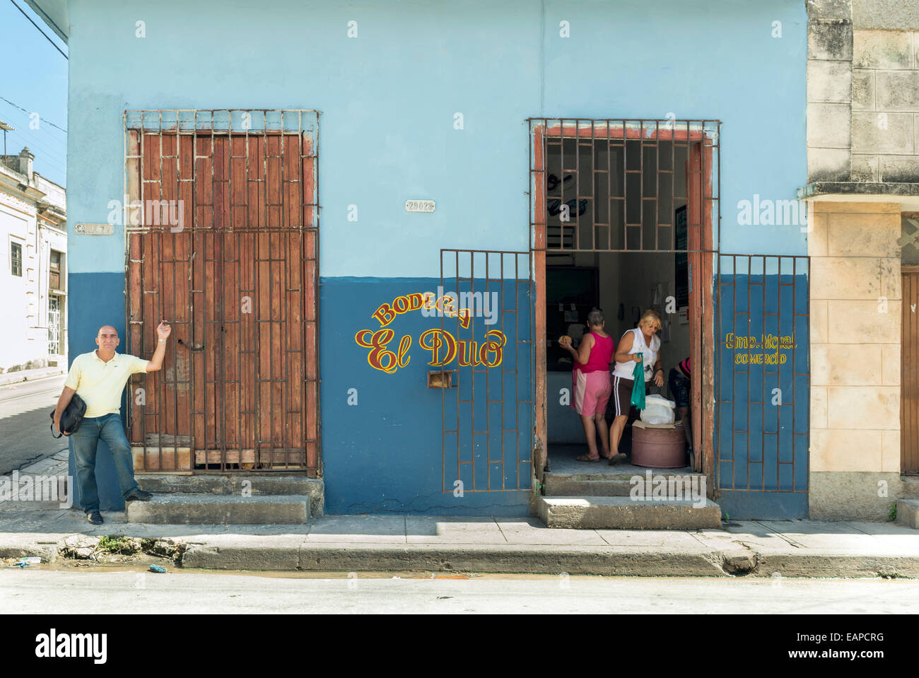 MATANZAS, CUBA - MAY 10, 2014:  Some people at the door of a typical warehouse on a downtown street Stock Photo
