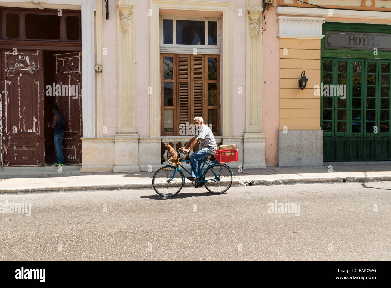 MATANZAS, CUBA - MAY 10, 2014:  Cuban cyclists and his dog  in a street of the colonial city of Matanzas, Cuba. Stock Photo