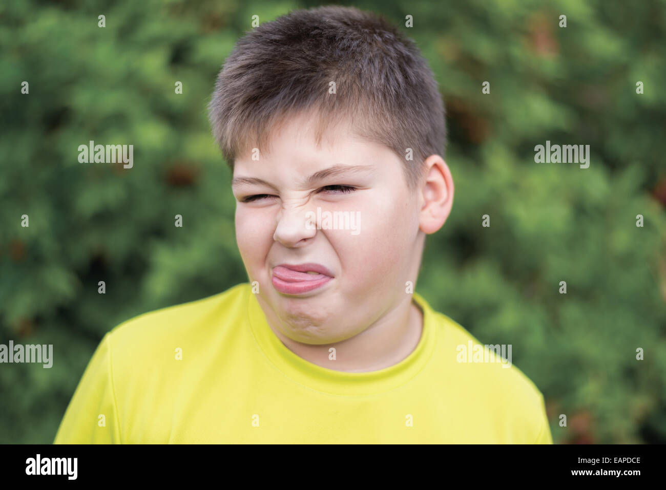 Boy grimaces in the summer park Stock Photo