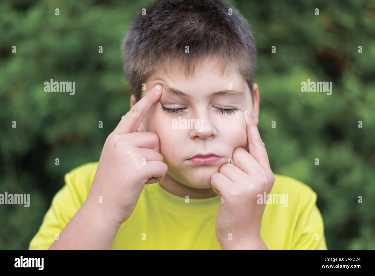 Boy grimaces in the summer park Stock Photo