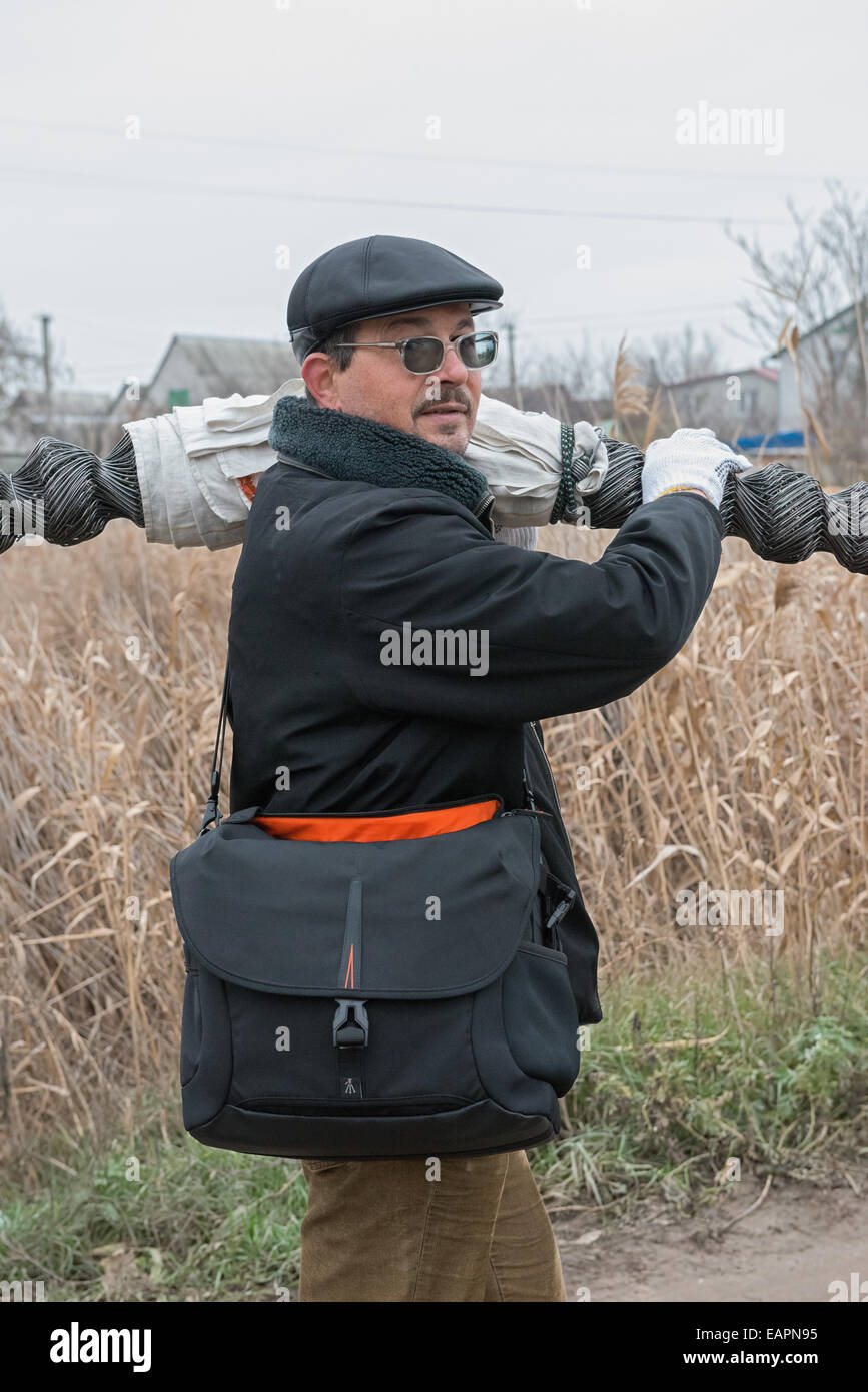 Mature man is carrying roll mesh netting over shoulder Stock Photo