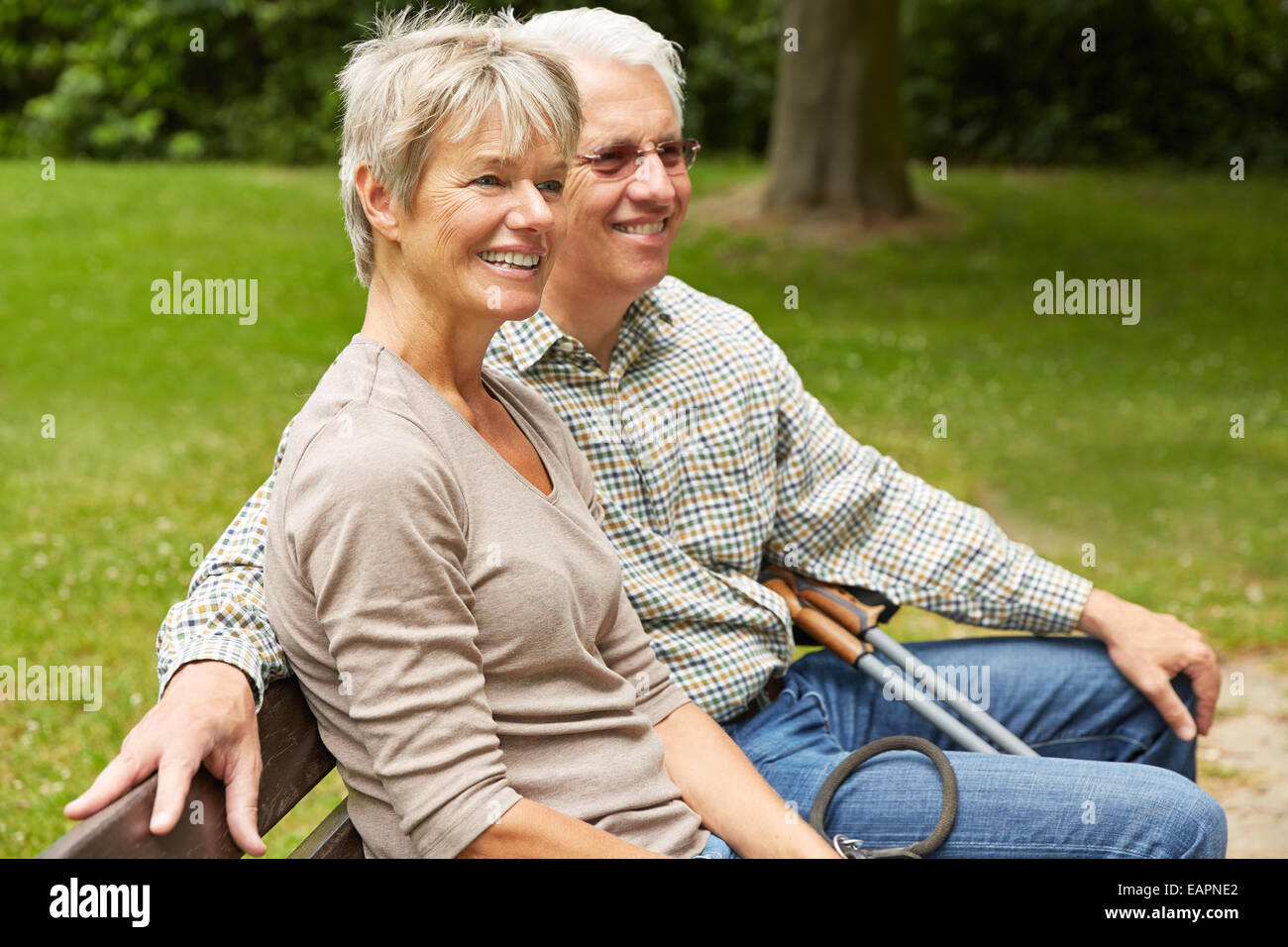 Happy senior couple sitting on a park bench in summer Stock Photo - Alamy