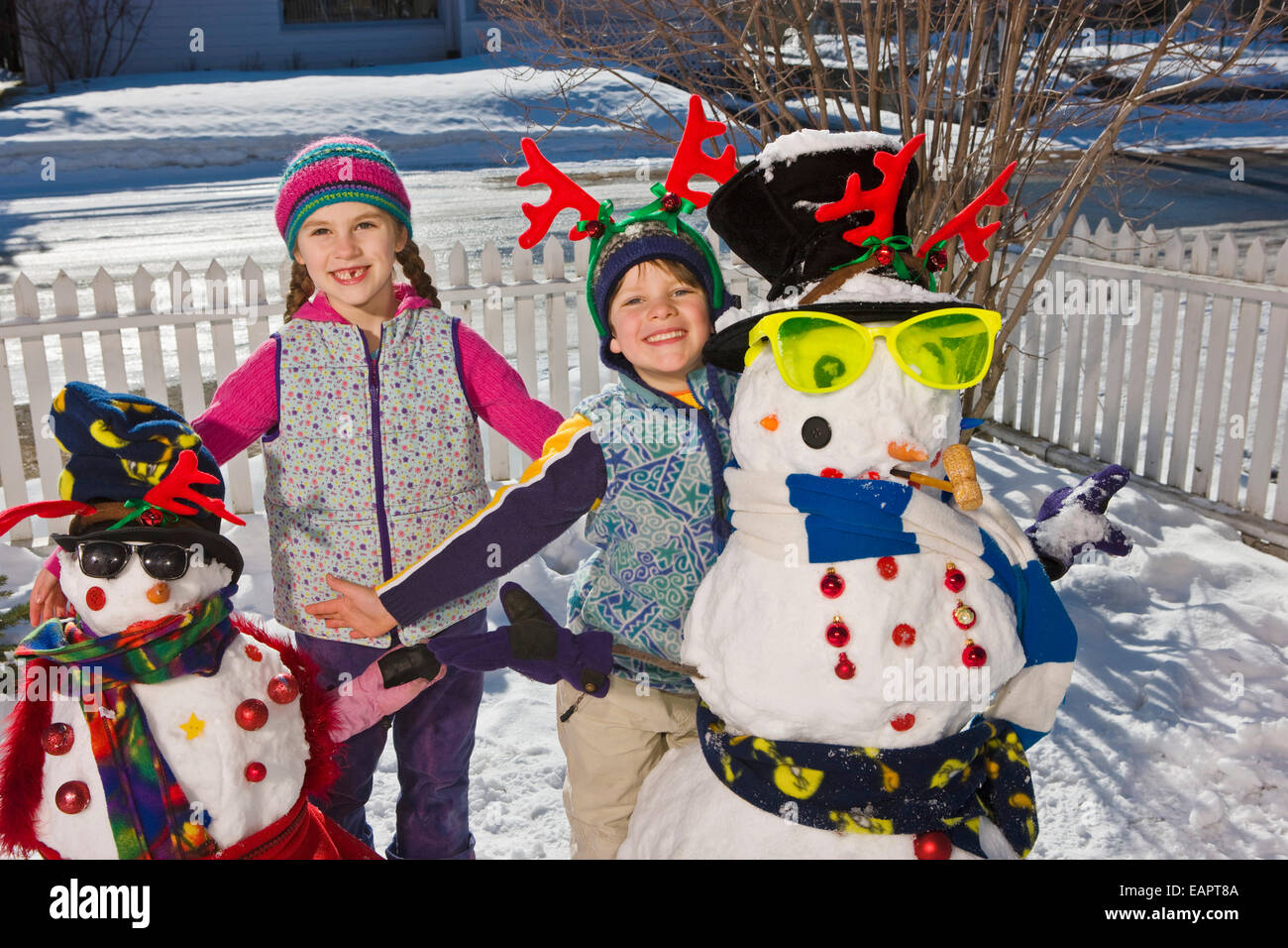 Brother & Sister Pose For A Picture With Their Snowmen In The Front ...