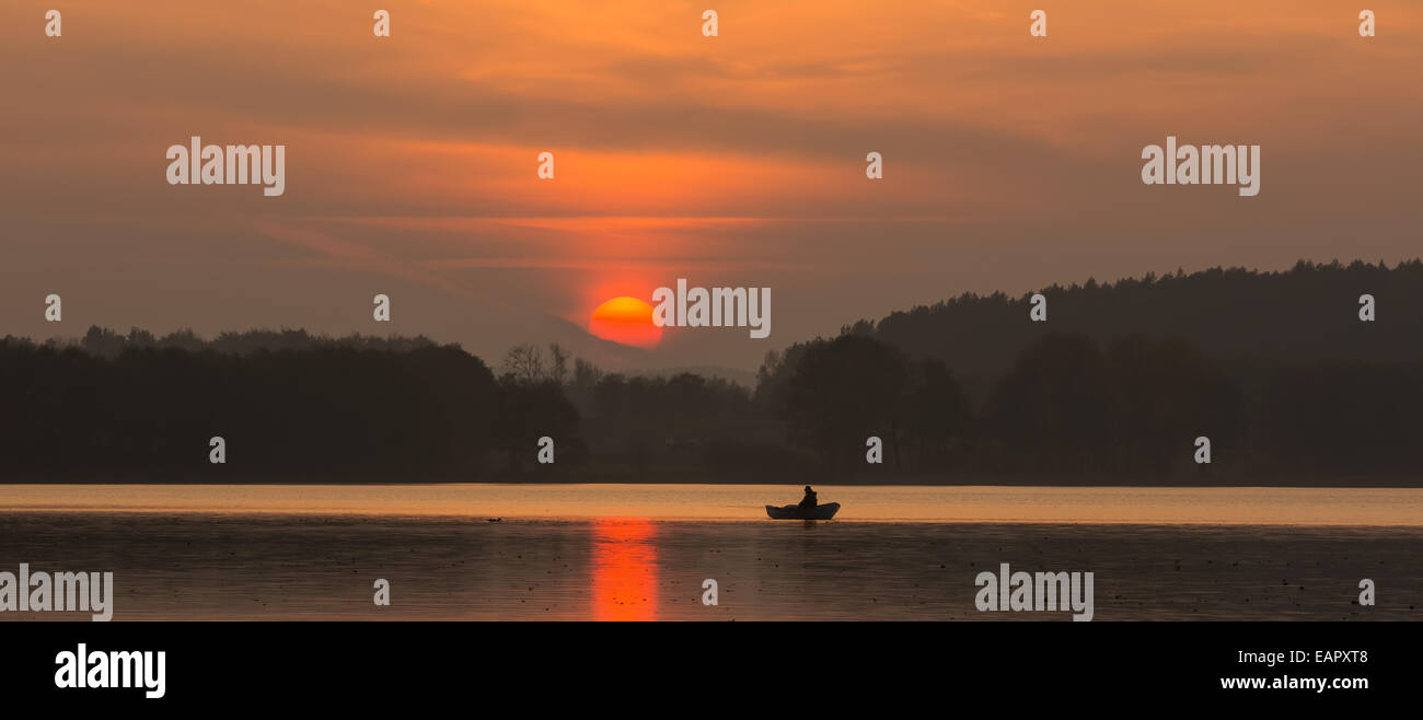 fisherman in boat on lake at sunset Stock Photo - Alamy