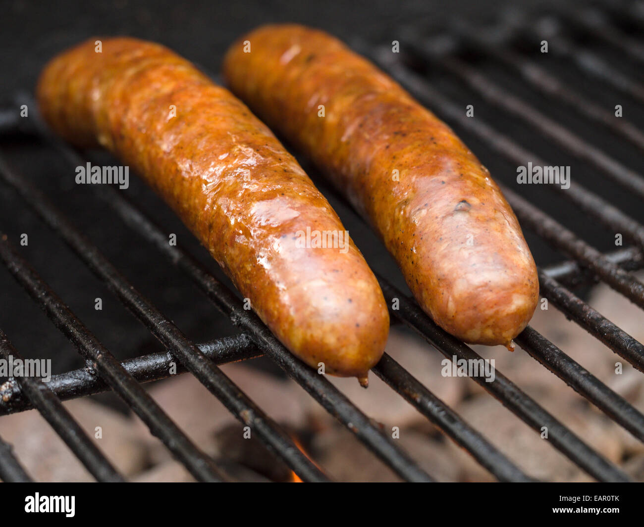 Two Sausages Heating. Two large sausages on a BBQ grill heating. The