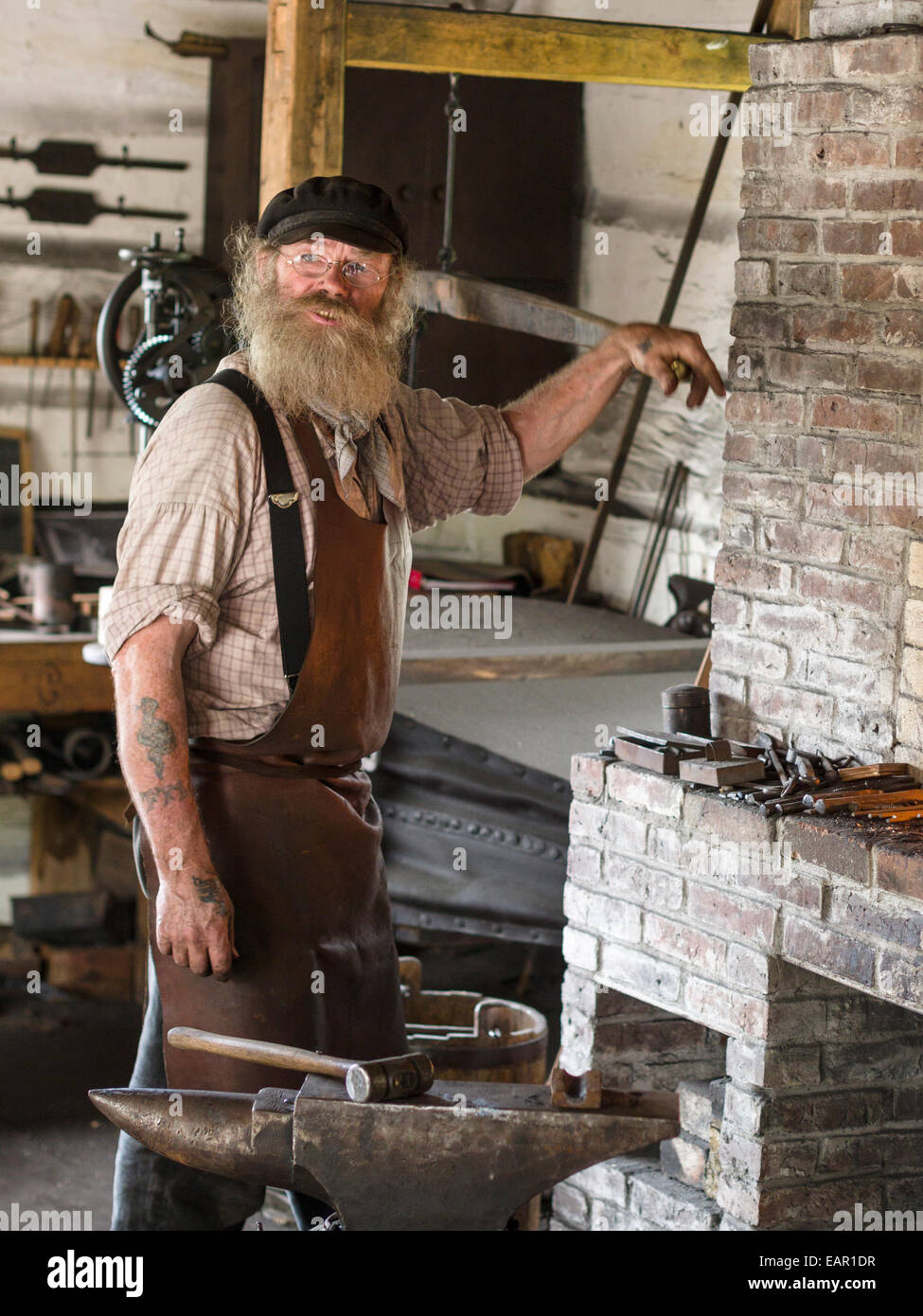 Blacksmith working the Bellows. A Blacksmith operates the bellows to raise the temperature of the fire for working iron Stock Photo