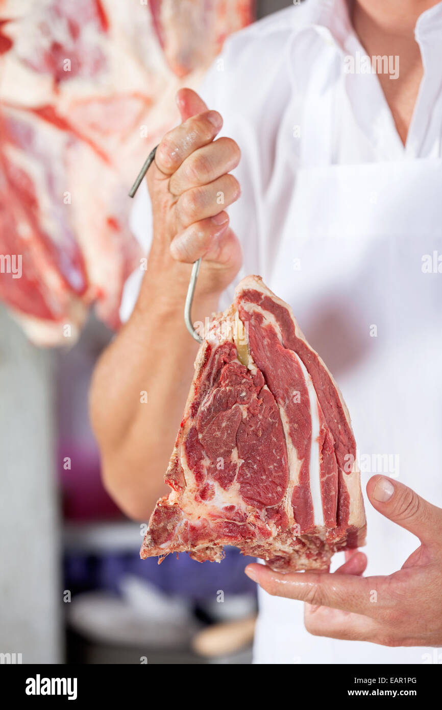 Butcher Holding Raw Meat With Hook Stock Photo