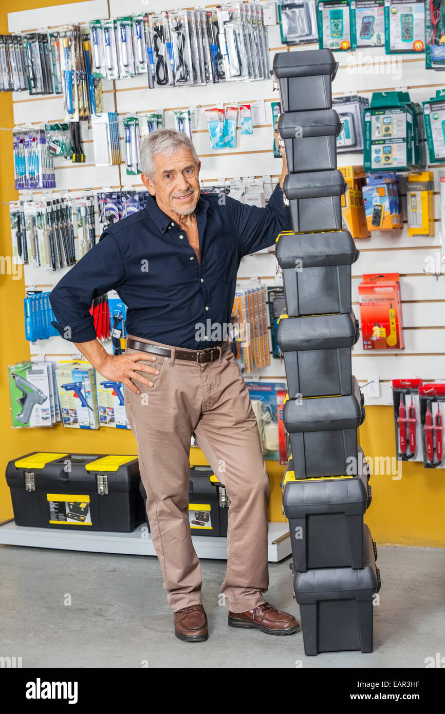 Senior Man Standing By Stacked Toolboxes In Shop Stock Photo