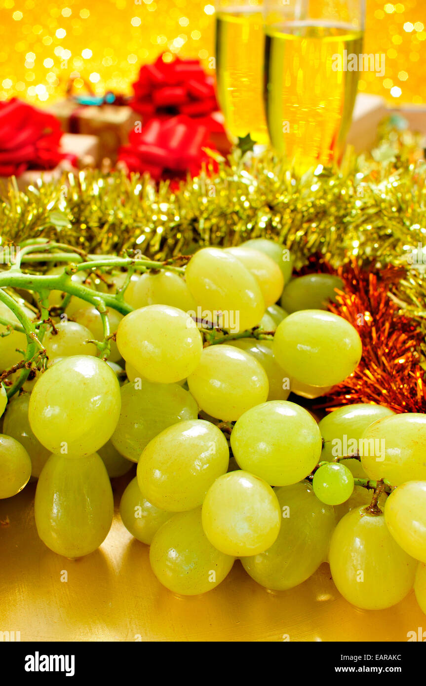 closeup of a bunch of grapes and glasses with champagne and some gifts in the background for the traditional celebration of the Stock Photo