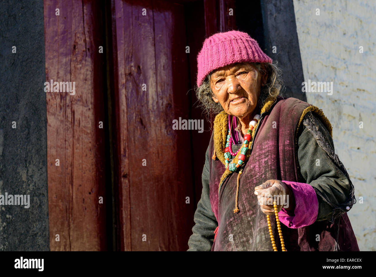 An old Ladakhi woman holding her mala, Buddhist prayer beads, at Lamayuru Gompa, Ladakh, Jammu and Kashmir, India Stock Photo