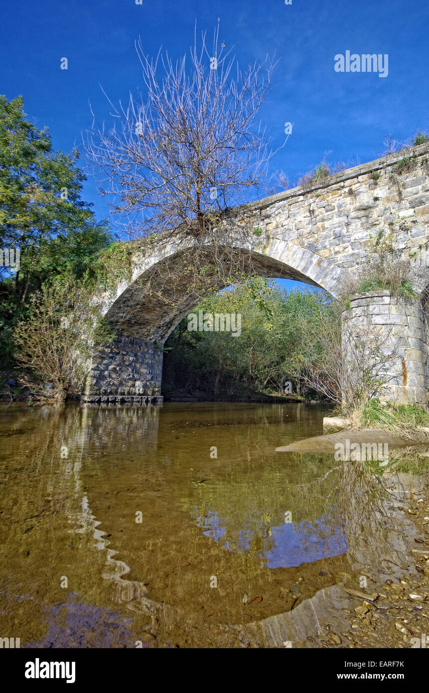 Abandoned stone bridge over a small river. Stock Photo
