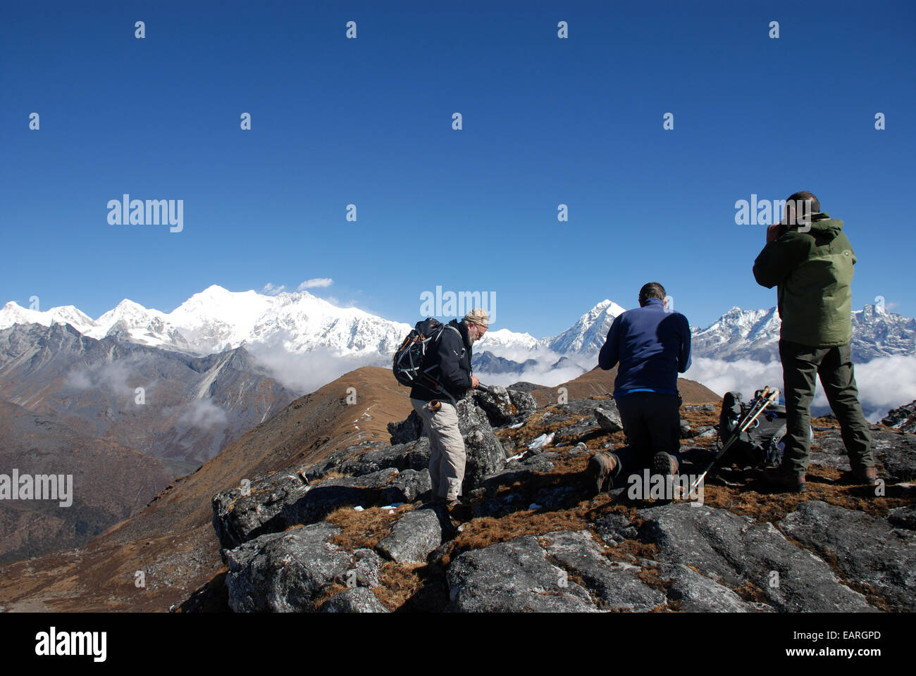 A group of trekkers on a high path in the Indian Himalayas with  snow covered mountain of Kangchenjunga  in the background Stock Photo