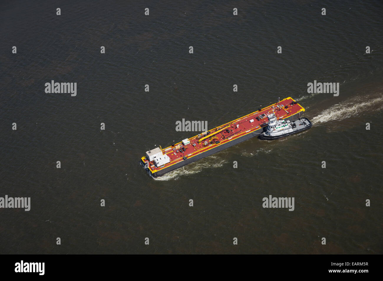 Aerial View Of Tug Boat Guiding Utility Barge Down River Stock Photo
