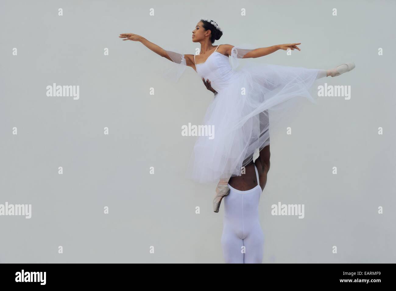 A ballet dancer holds his partner up in the air. Stock Photo
