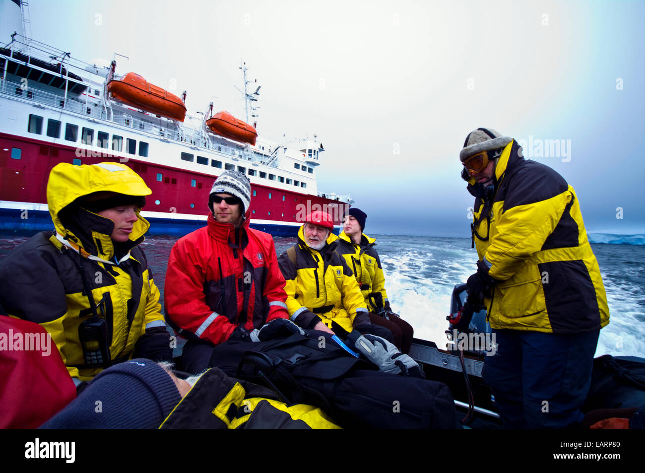 An Antarctic expedition crew in waterproof jackets in a zodiac boat. Stock Photo