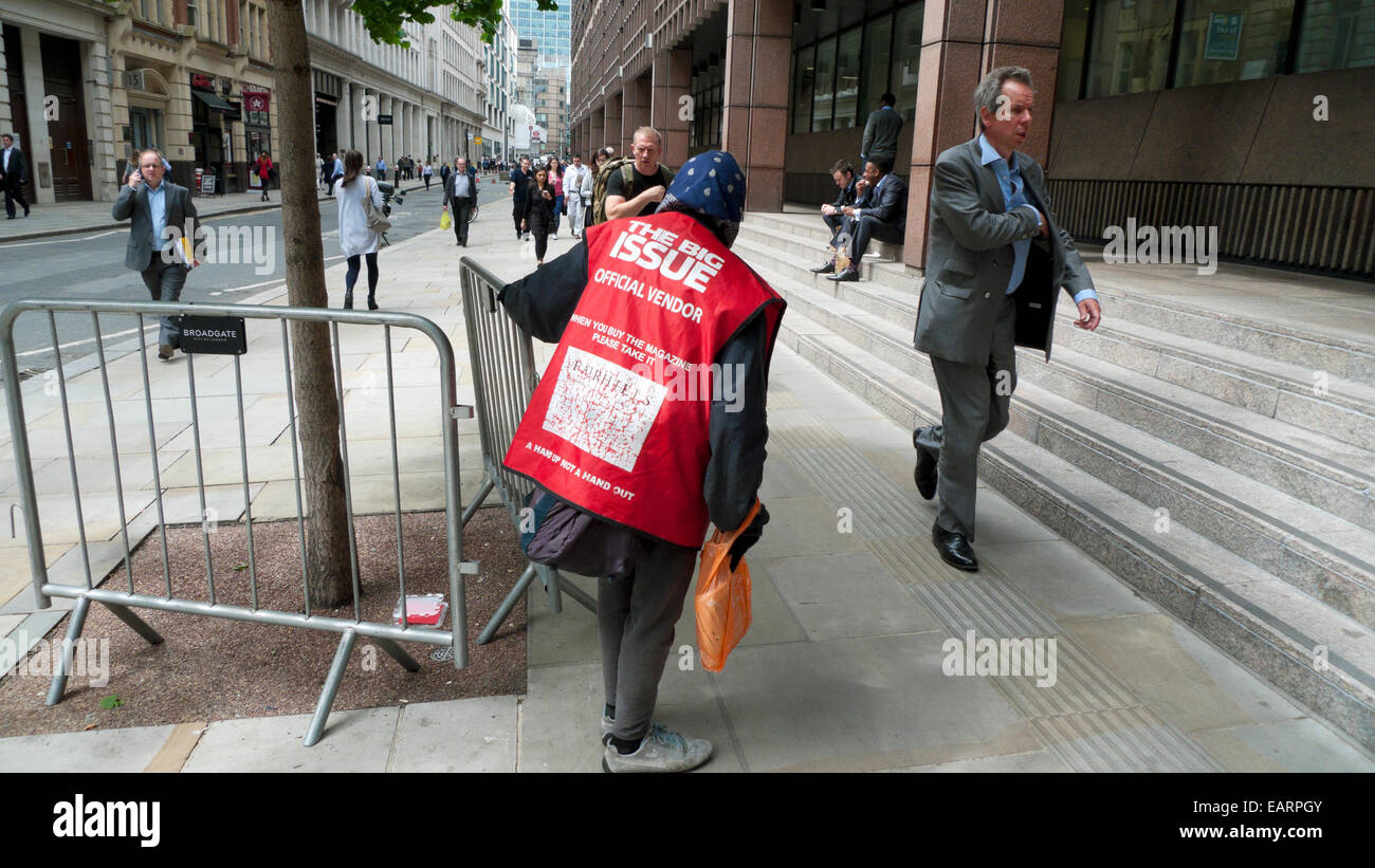 Businessman walking past a Big Issue seller vendor selling magazines near Broadgate Circle in the City of London Square Mile UK   KATHY DEWITT Stock Photo