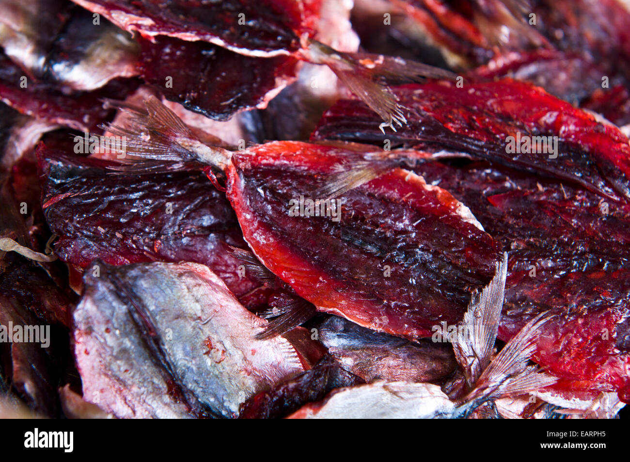Dried bright red filleted fish for sale in an open air market stall. Stock Photo