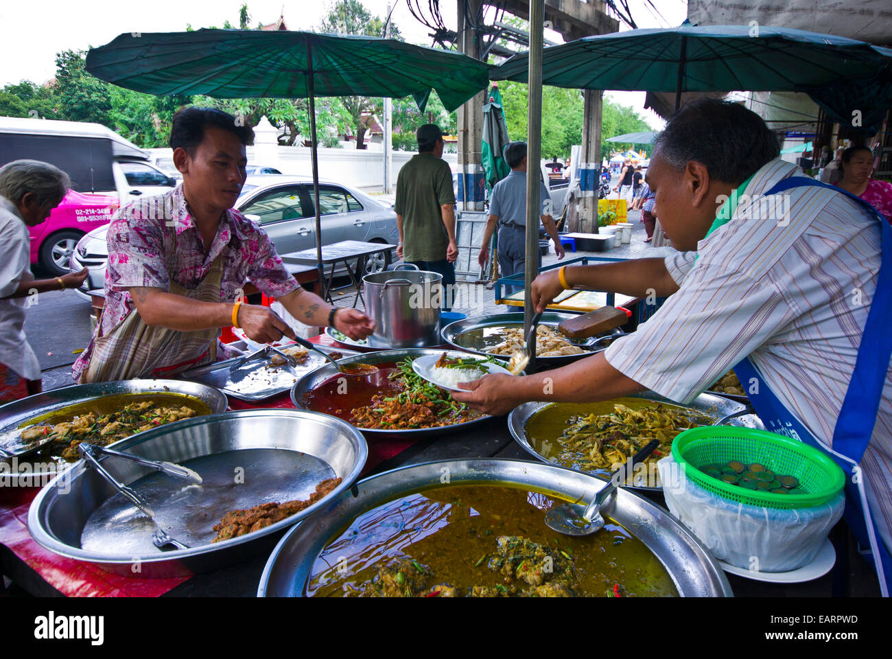 A stall owner serves a customer a lunch of rice and spicy beans. Stock Photo