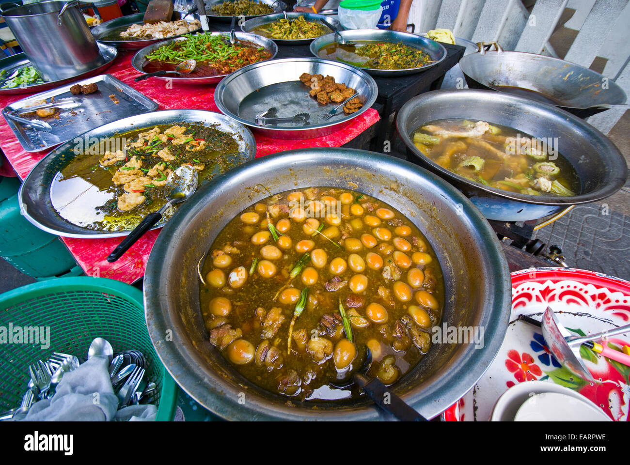 Large silver bowls contain curry and spicy eggs, chicken and seafood. Stock Photo