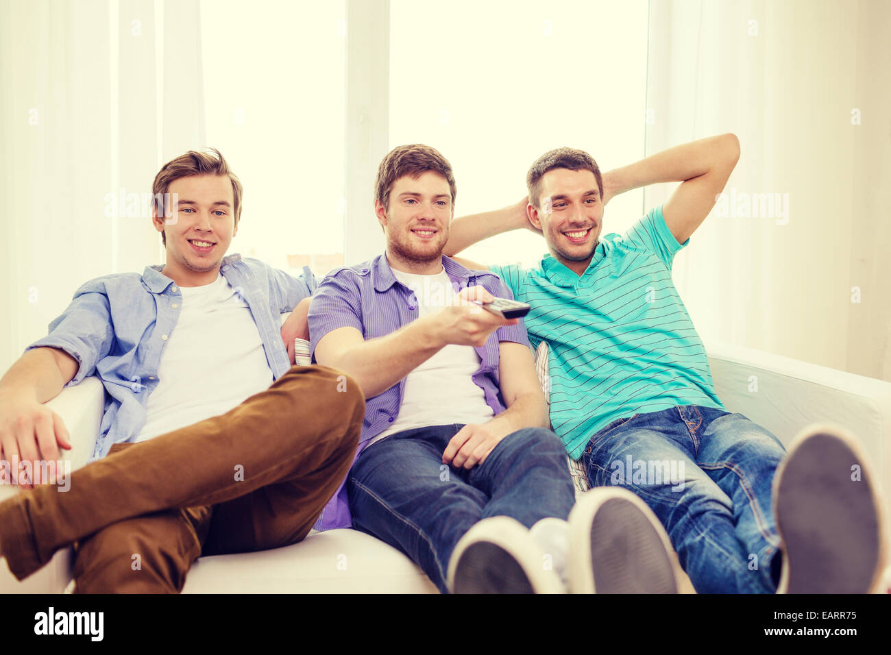 smiling friends with remote control at home Stock Photo - Alamy