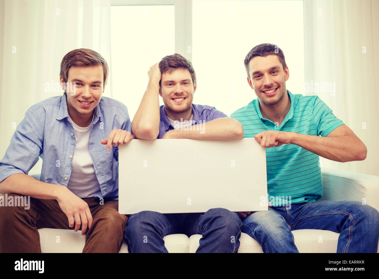 smiling male friends holding white blank board Stock Photo