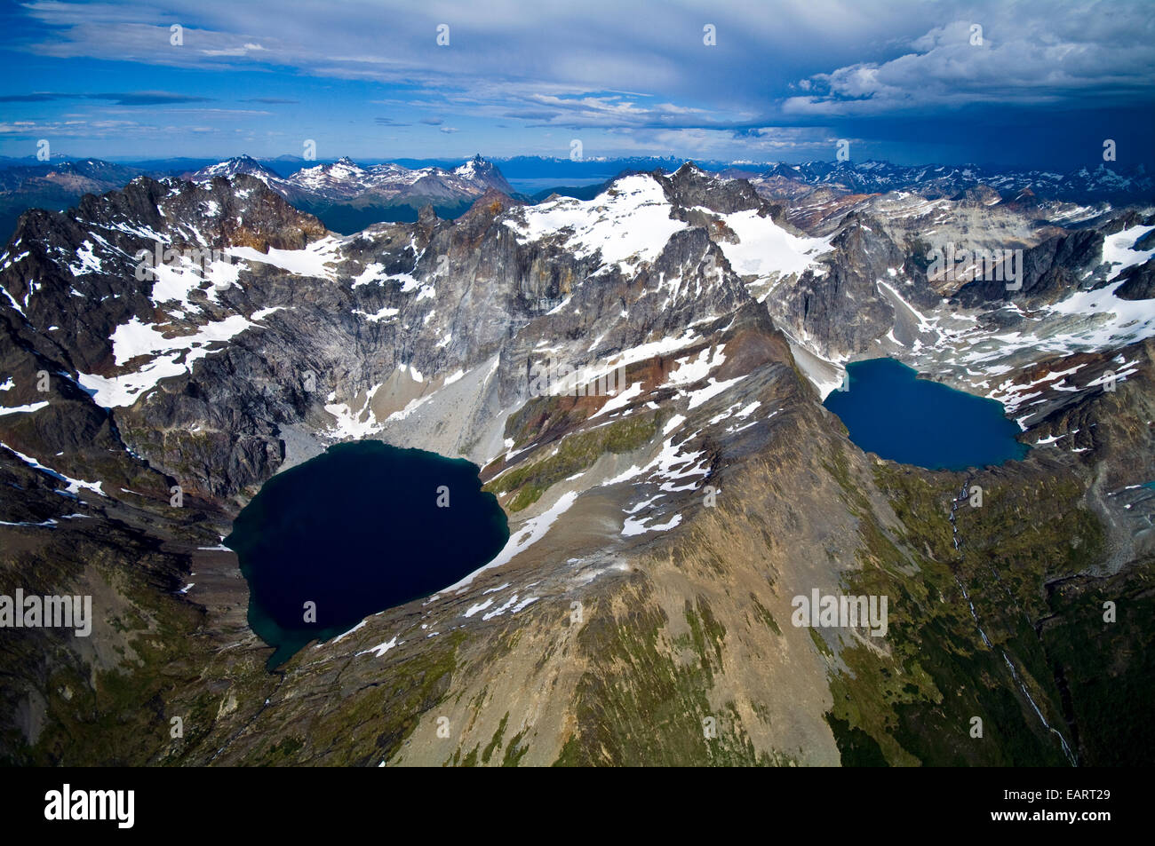 Snow and ice draped peaks cradle two remote turquoise glacial lakes. Stock Photo