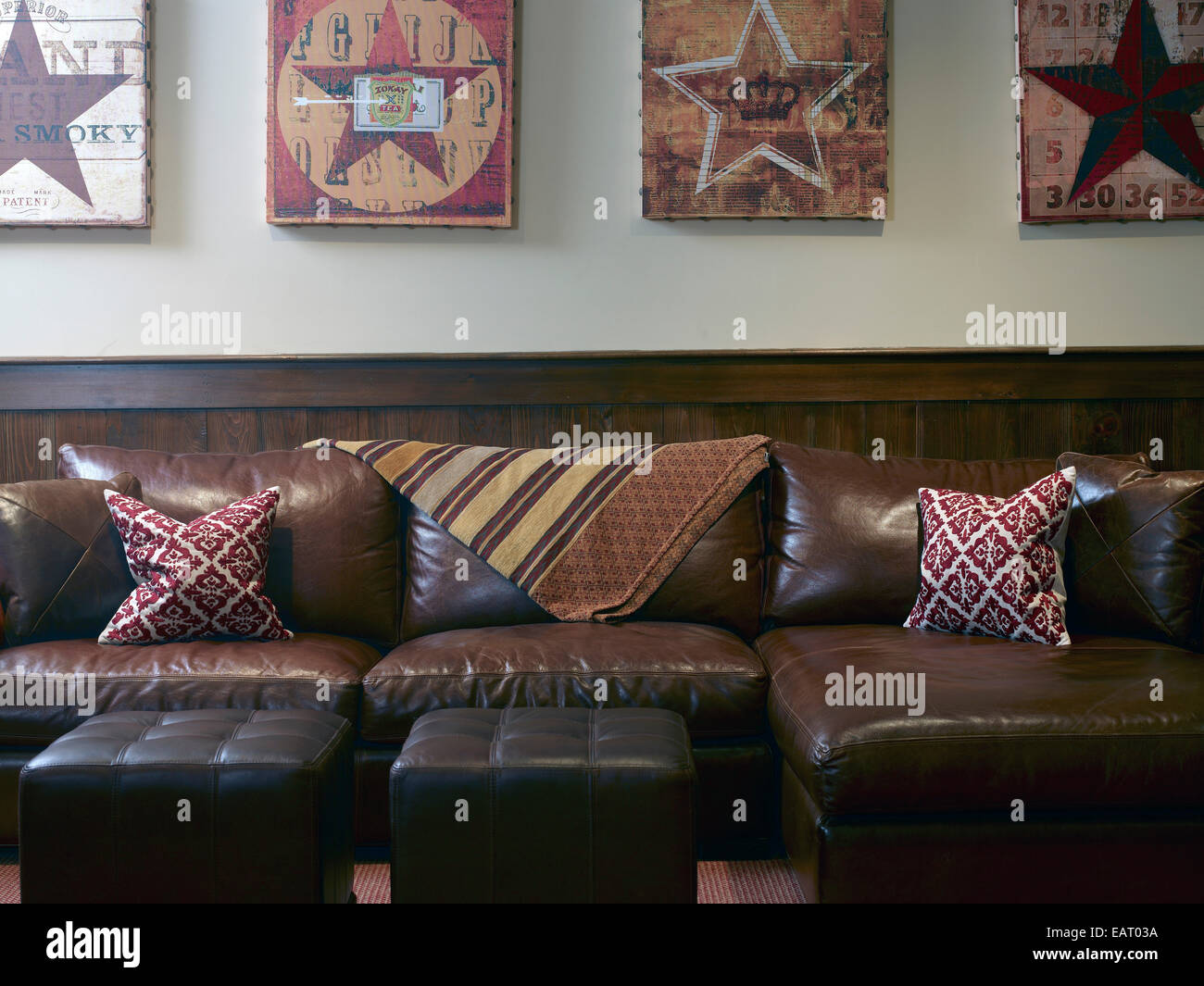 Artwork on wall above leather sofa and footstools, USA Stock Photo