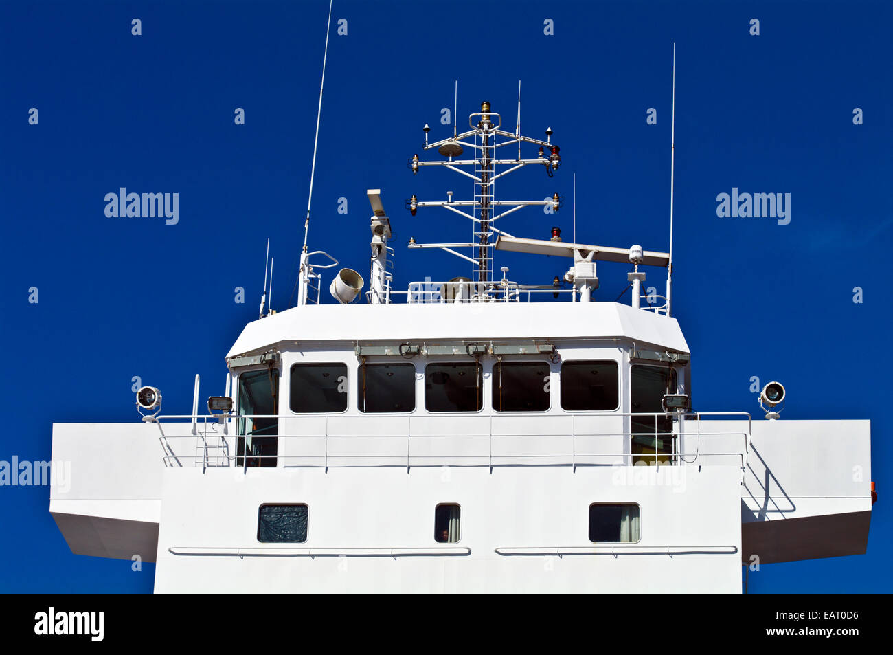 A cargo ship's bridge and control deck with antenna and spotlights