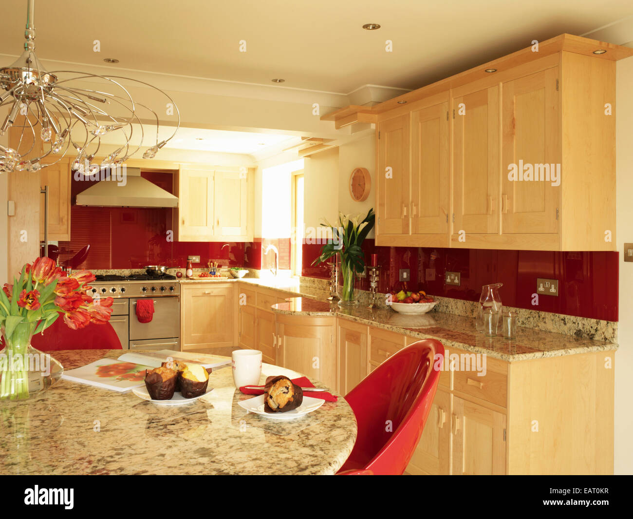 Dining table with red chairs in kitchen with fitted units Stock Photo