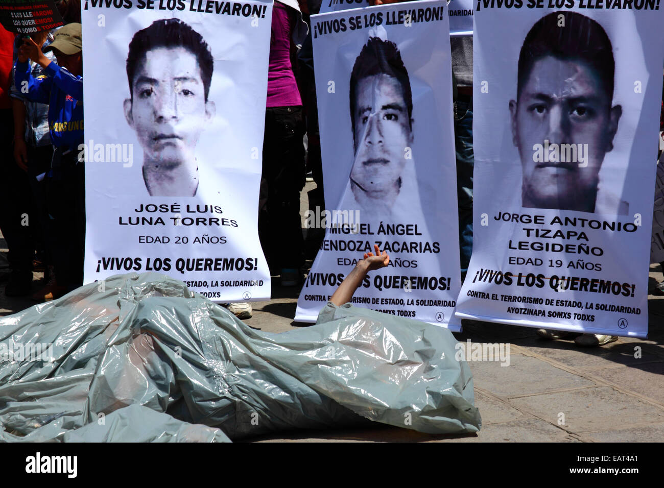 La Paz, Bolivia. 20th November, 2014. A protester lies on the ground in a plastic bag representing a body bag before a march to demand justice for the 43 missing students in Mexico and protest against the Mexican government's handling of the case and corruption. Today has been designated a Global Day of Action for Ayotzinapa; a national strike is planned in Mexico and many protests are taking place worldwide to show support. The students disappeared after clashing with police on the night of 26th September in the town of Iguala. Credit:  James Brunker / Alamy Live News Stock Photo