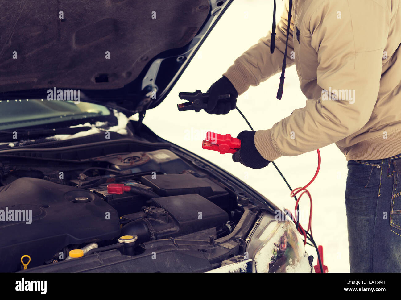 closeup of man under bonnet with starter cables Stock Photo