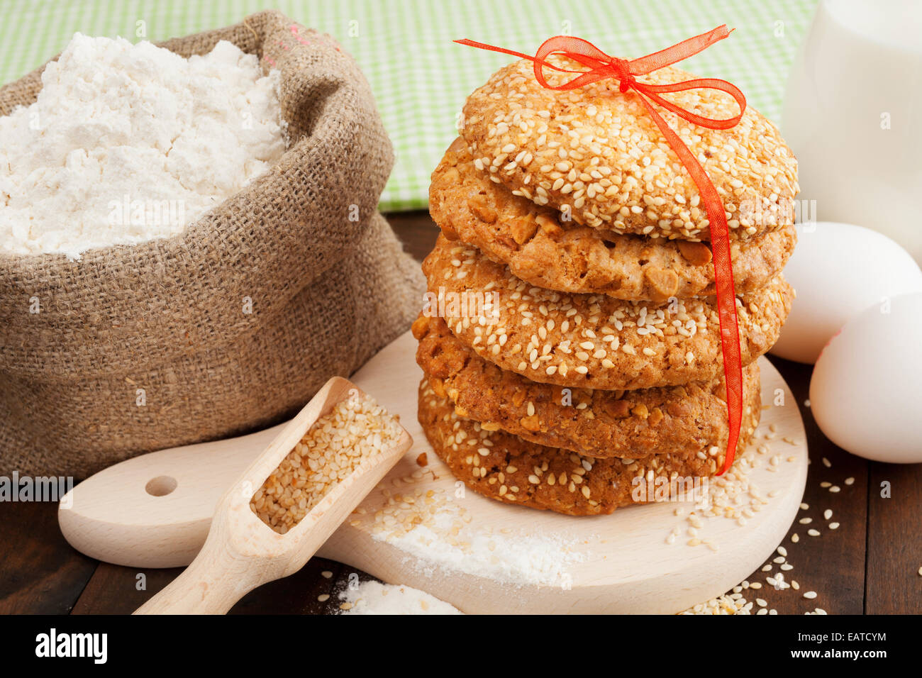 cookies with sesame seeds, flour and eggs on kitchen table Stock Photo