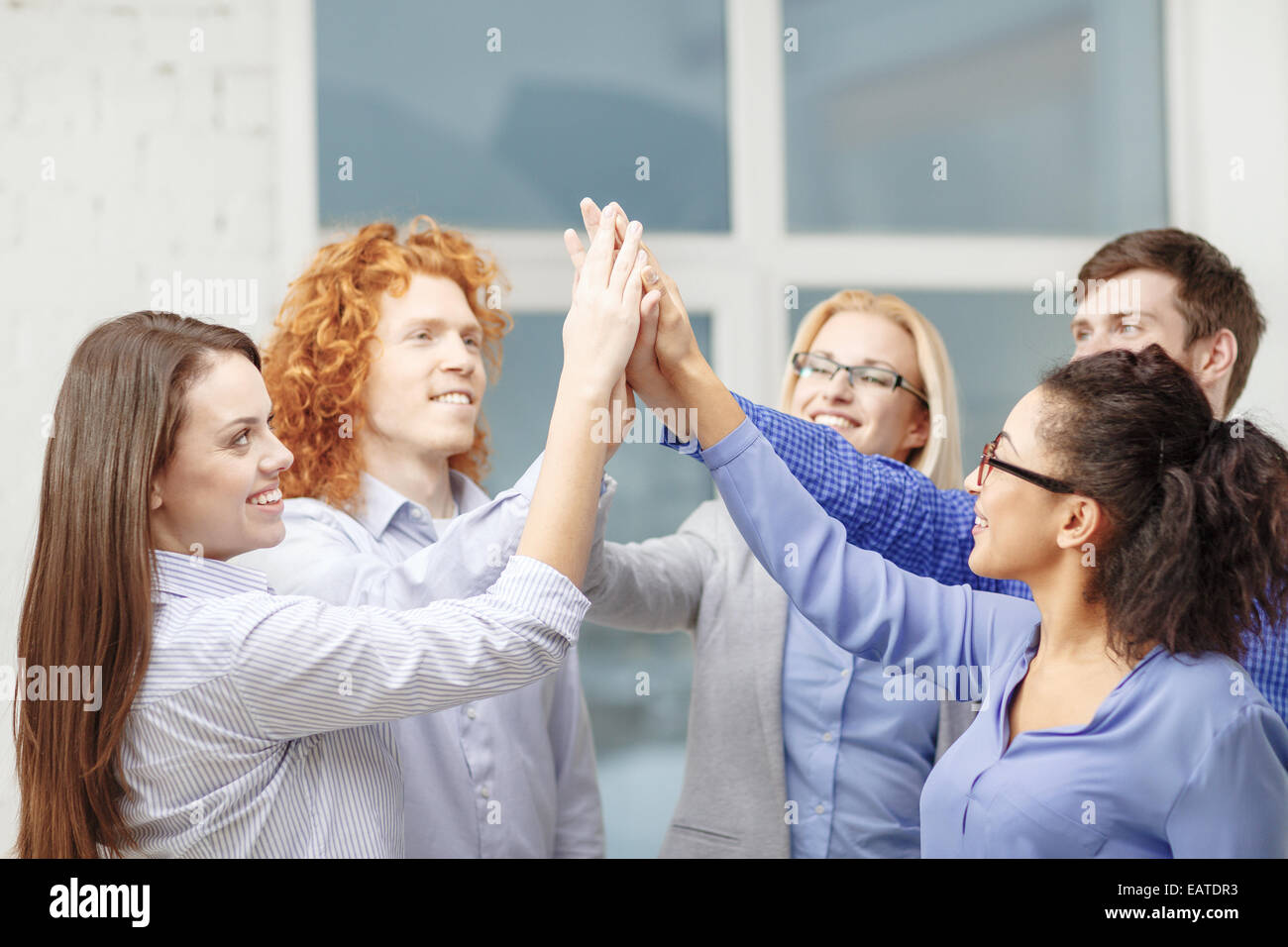 creative team doing high five gesture in office Stock Photo
