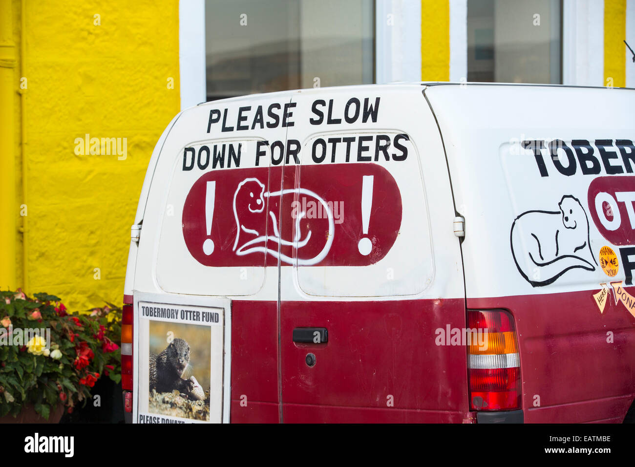 An Otter charity van on the promenade of Tobermory on the Isle of Mull, Scotland, UK, with its colouful painted shops. Stock Photo