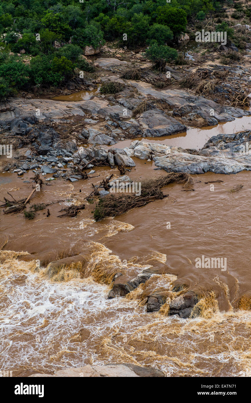 Raging flood waters cascading over rocky outcrops in a forest. Stock Photo